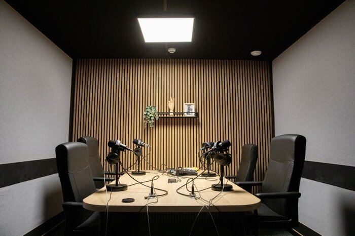 studio de podcast cosy avec 4 micros, chaises et équipement d'enregistrement de podcast
