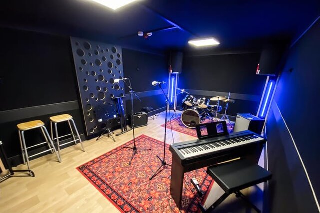 Energieke zangeres die repeteert met een pianist en een drummer in een studio