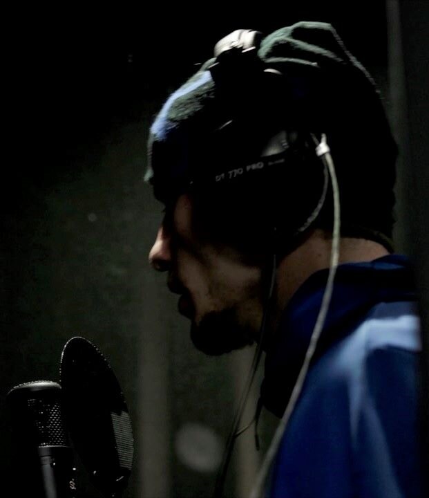 Rapper wearing headphones in front of a microphone in a vocal recording booth