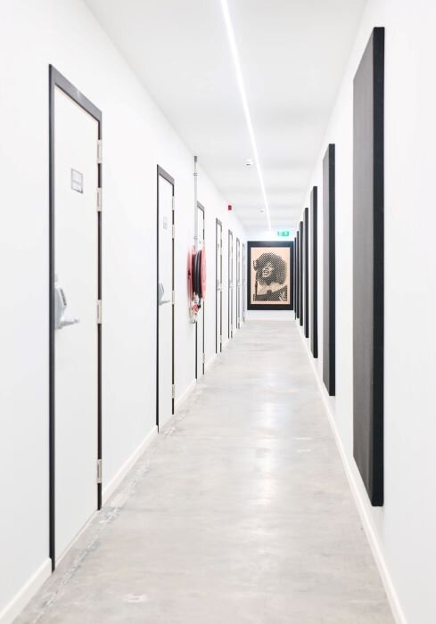 Couloir de studios de musique avec murs et portes blanches et des panneaux acoustiques noirs à Bruxelles