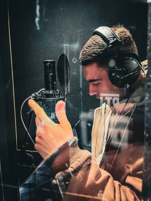 Chanteur devant un micro avec un casque audio sur la tête dans la cabine vocale d'un studio d'enregistrement à Liège