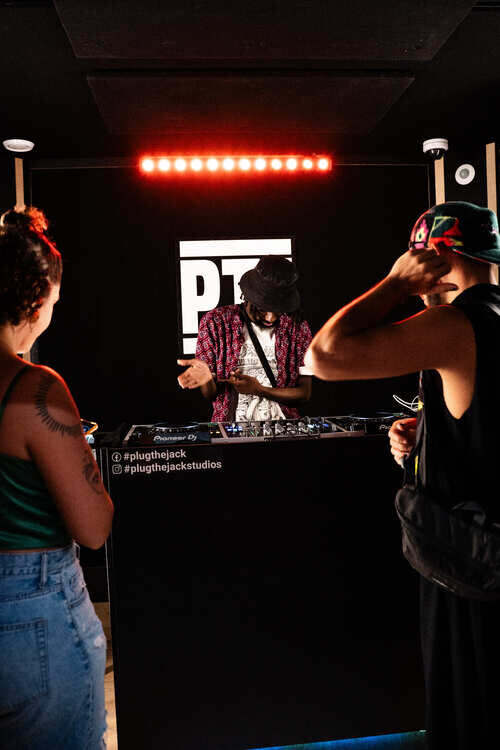 DJ mixing for two friends in a DJ studio with red LED lights