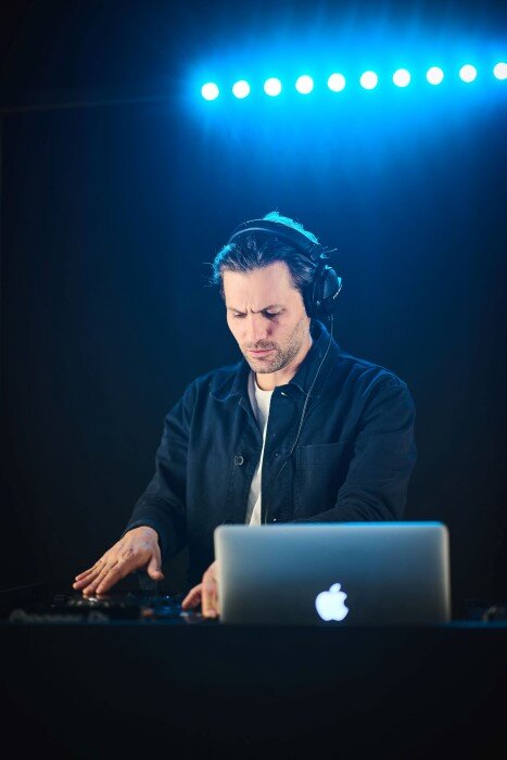 Man aan het mixen in DJ-studio, met koptelefoon en verlichting in luik