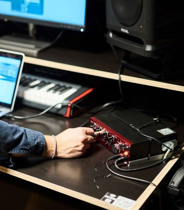 Man gebruikt een Focusrite Clarett 4Pre+ geluidskaart in een opnamestudio in brussel