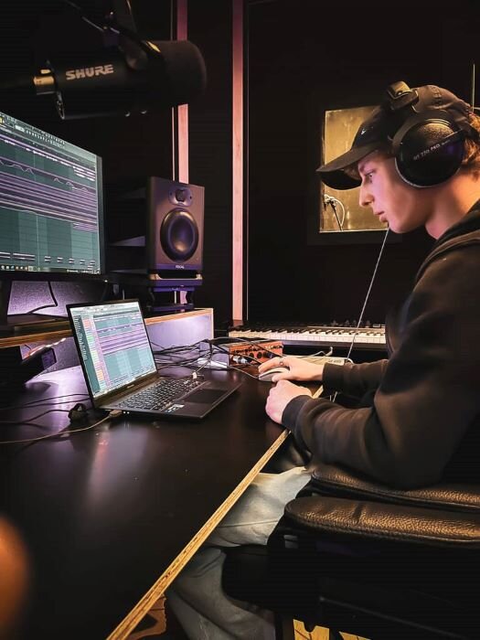 Geluidstechnicus voor een scherm met luidsprekers in een opnamestudio, zangcabine op de achtergrond in antwerpen