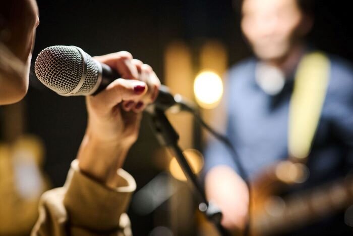 Singer and guitarist in music studio for recording session. | © Plug The Jack