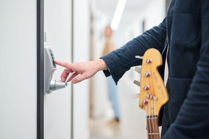 Bassist entering access code at music studio for recording session. | © Plug The Jack