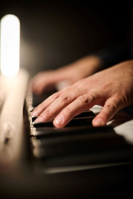 Hands on a stage piano in a band rehearsal space. | © Plug The Jack